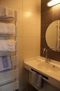 ein Badezimmer mit einem Waschbecken, einem Spiegel und Handtüchern in der Unterkunft Hôtel Restaurant Oberlé in Kilstett