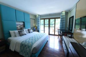 ein Schlafzimmer mit einem großen Bett und einem Balkon in der Unterkunft Tugawe Cove Resort in Colongcocon