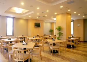 a restaurant with wooden tables and chairs and a tv at Hotel Route-Inn Isahaya Inter in Isahaya