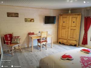 een slaapkamer met een bed, een bureau en een televisie bij La Ferme de Là-haut B&B in Le Haut-du-Them