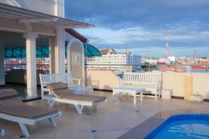 a balcony with white benches and a swimming pool at LK Mansion in Pattaya