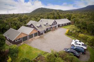 an aerial view of a house with cars parked in the driveway at Patuha Rainforest Retreat in Okato