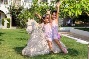 two girls are sitting on a statue of a horse at Alexandra Beach Spa Resort in Potos