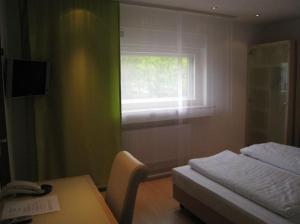 Schlafzimmer mit einem Bett, einem Tisch und einem Fenster in der Unterkunft Hotel Barbarina in Tübingen