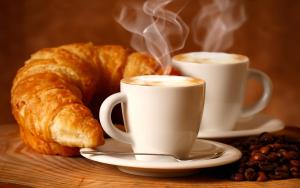 zwei Tassen Kaffee und ein Croissant und Kaffeebohnen in der Unterkunft Alen Bar Hotel in Tirana
