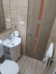 łazienka z toaletą, umywalką i drzwiami w obiekcie Onalisa w mieście Arad