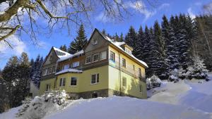 ペツ・ポト・スニェシュコウにあるUbytování Javorの雪中の黄色い家