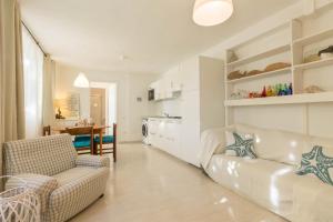 a living room with a white couch and a kitchen at Follow the Sun in Cagliari