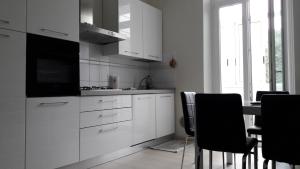 ヴァード・リーグレにあるResidenza Lux fronte mareのキッチン(白いキャビネット、テーブル、椅子付)