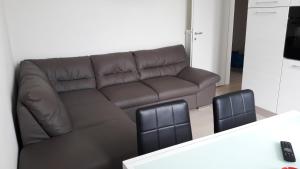 un soggiorno con divano marrone e 2 sedie di Residenza Lux fronte mare a Vado Ligure
