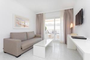 a white living room with a couch and a table at Aparthotel Duquesa Playa in Santa Eularia des Riu