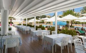 
a patio area with tables, chairs and umbrellas at MarSenses Paradise Club in Cala en Bosc
