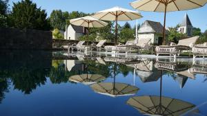 a pool of water with chairs and umbrellas at Appartements & Spa de la Marine Loire in Montsoreau