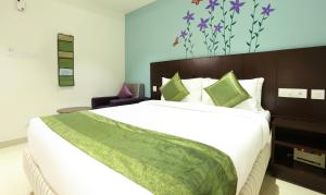 a bedroom with a large bed with a green blanket on it at Treebo Trend C Plaza in Vijayawāda