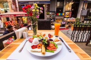une assiette de nourriture sur une table avec un vase de fleurs dans l'établissement Kuzen Otel, à Istanbul