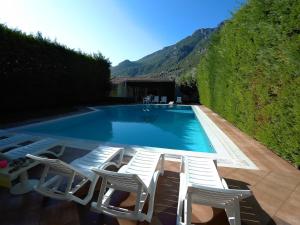 a swimming pool with lounge chairs next to a hedge at Diamond Apartments in Agios Konstantinos Fthiotida