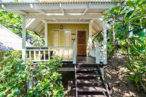 a porch of a yellow house with a white roof at Cocohut Beach Resort Koh Phangan in Haad Rin