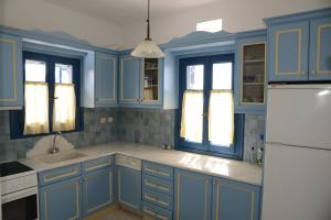 アギオス・イオアニスにあるTinos Porto Villasのキッチン(青いキャビネット、白い冷蔵庫付)