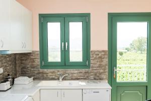 a kitchen with green cabinets and a sink and two windows at Villa Kampos in Vanáton