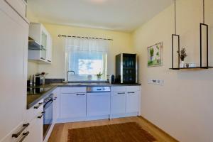 a kitchen with white cabinets and a sink at Nikolaier Weinblick - Ferienwohnung Muskateller in Sankt Nikolai ob Draßling