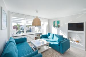 a living room with two blue couches and a tv at Pomorskie Apartamenty Ceynowy 1 Deluxe in Sopot