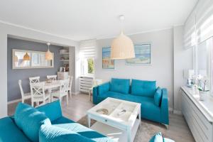 a living room with a blue couch and a table at Pomorskie Apartamenty Ceynowy 1 Deluxe in Sopot
