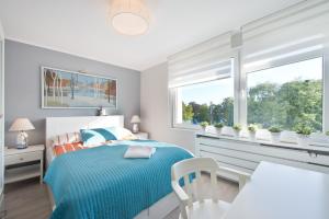 a bedroom with a bed and a table and two windows at Pomorskie Apartamenty Ceynowy 1 Deluxe in Sopot