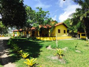 una casa amarilla con un patio delante en Casa Amarela na praia 14 pessoas, en Ponta da Tulha