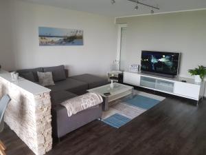 ein Wohnzimmer mit einem Sofa und einem TV in der Unterkunft Beach Apartment in Wilhelmshaven
