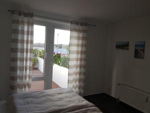 ヴィルヘルムスハーフェンにあるBeach Apartmentのベッドルーム1室(ベッド1台付)、スライド式ガラスドアが備わります。