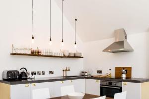 a kitchen with white cabinets and black counter tops at The Workshop @ The Grange in Lydd