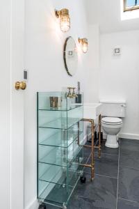 a bathroom with a glass cabinet and a toilet at The Workshop @ The Grange in Lydd