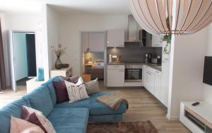a living room with a blue couch and a kitchen at Apartments Bogner in Marktbergel