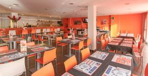 restauracja z pomarańczowymi ścianami, stołami i krzesłami w obiekcie H2 Fuenlabrada w mieście Fuenlabrada