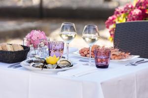 una mesa con dos copas de vino y platos de comida en Hotel Kastel & Spa avec piscine d'eau de mer chauffée, en Bénodet