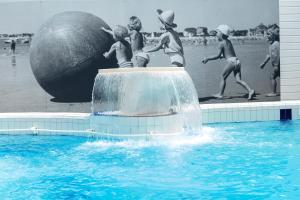 eine Gruppe von Kindern, die in einem Pool mit einem großen Ball spielen in der Unterkunft Hotel Kastel & Spa avec piscine d'eau de mer chauffée in Bénodet