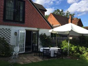 een patio met een tafel en een parasol bij Hurstbourne in Camberley