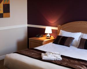 um quarto de hotel com uma cama e um candeeiro sobre uma mesa em The Angel View Hotel em Gateshead