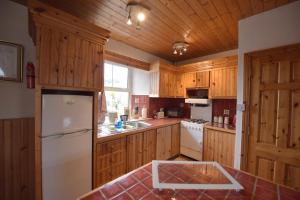 eine Küche mit Holzschränken und einem weißen Kühlschrank in der Unterkunft The Old School House in Clifden