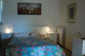 una camera da letto con un letto con un piumone colorato e due lampade di B&B Santu Larentu a Ozieri