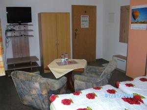 Zimmer mit einem Tisch, Stühlen und einem Bett in der Unterkunft Pension Schwalbe in Zwenkau