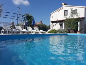 a swimming pool with chairs and a house at Apartments Angela in Žbandaj