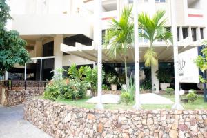 a building with palm trees in front of it at Flat Oeste La Residence in Goiânia
