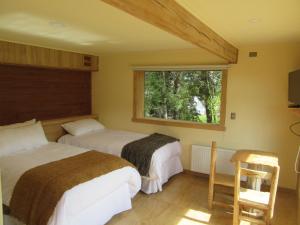 a bedroom with two beds and a window at Hostal Casa Bosque in Dalcahue