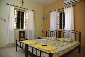 a bedroom with a bed with a cross in the window at Niki Guest House in Candolim
