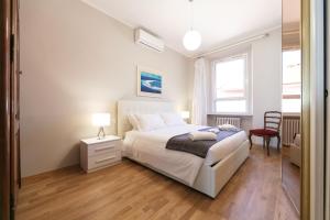 1 dormitorio con 1 cama blanca y 1 silla roja en Milan Retreats, en Milán