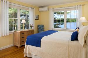 a bedroom with a large bed and two windows at Wolf Cove Inn in Poland Spring