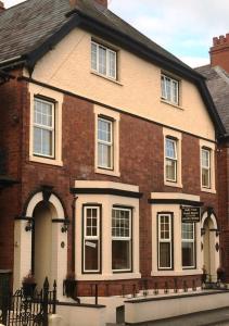 dom z czerwonej cegły z ławką przed nim w obiekcie Holly Tree Guest House w mieście Hereford