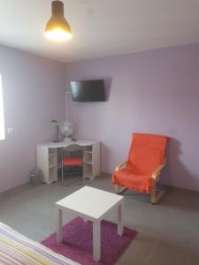 a living room with a red chair and a table at l'étoile de la fontchevrière in Neuvy-Saint-Sépulchre