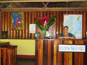 Une femme debout derrière un podium avec un vase de fleurs dans l'établissement Crystal Paradise Resort, à San Ignacio